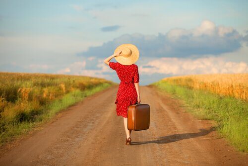 bavuluyla yürüyen şapkalı kadın