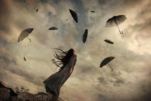Fırtınalı havada uçan şemsiyelere bakan kadın