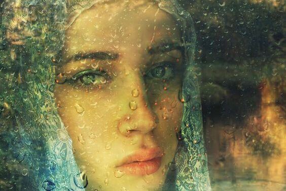 yağmur damlalı camın ardından bakan kadın
