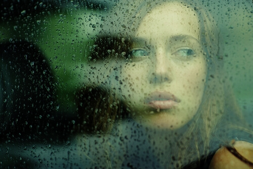 camdan bakan kadın ve yağmur damlaları