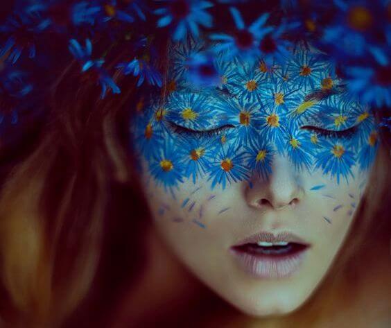 mavi çiçeklerden oluşan maskesi olan kadın