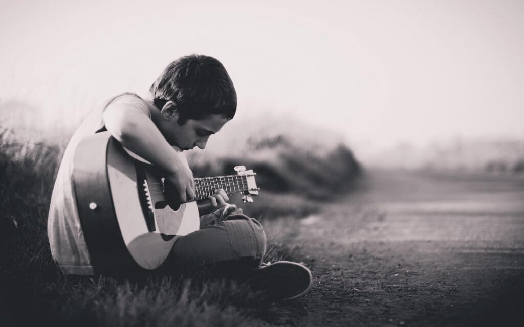 çocuk oturmuş gitar çalıyor