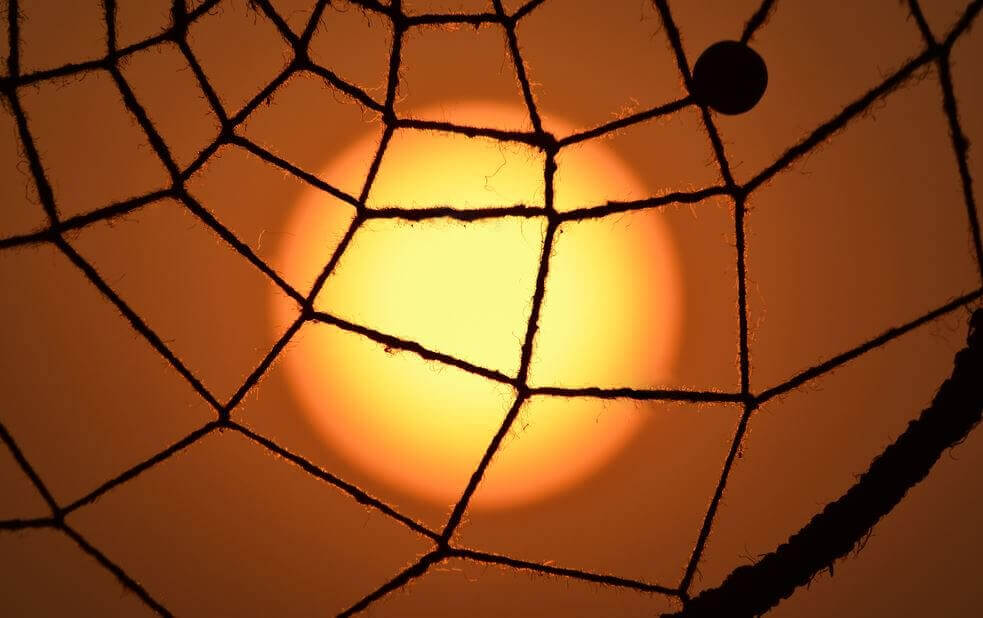 örümcek ağı şeklinde ip arkasında puslu güneş