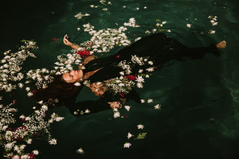 suda çiçeklerle duran elbiseli kadın