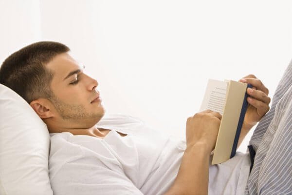 adam yatakta kitap okuyor