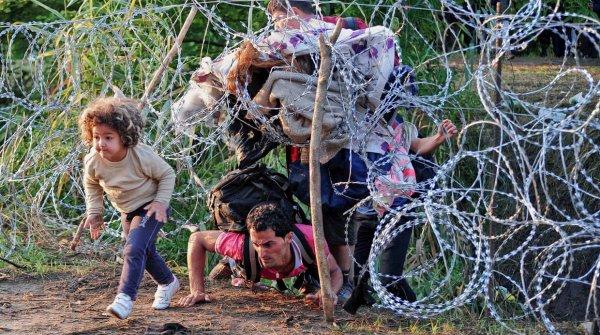 dikenli telleri aşan mülteci baba ve çocuk