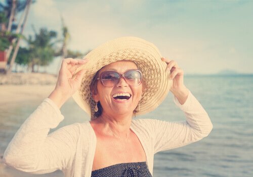 deniz kenarında şapkalı orta yaşlı mutlu kadın