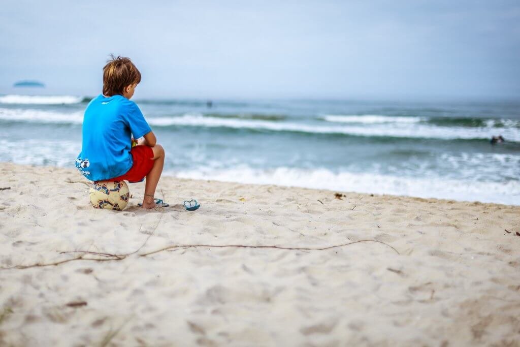 topun üzerinde oturup denizi seyreden çocuk