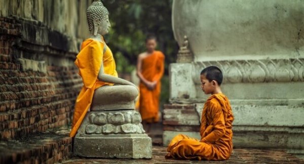 Buda heykeli önünde oturmuş çocuk