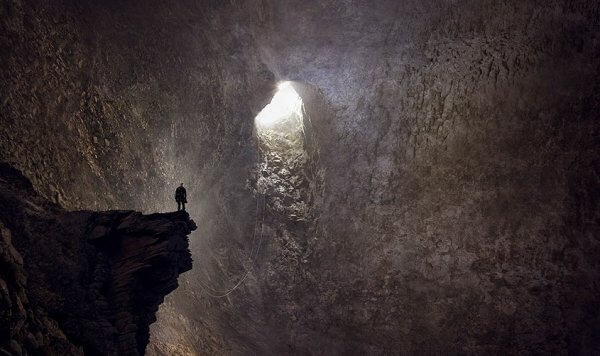 mağara çıkışına bakan kişi