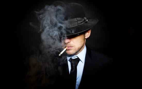 siyah takım elbiseli adam sigara içiyor