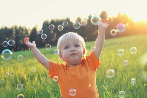 çayırda baloncuklarla oynayan minik çocuk