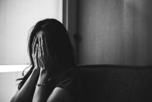 Bir kadın, ellerini yüzüne koymuş şekilde duruyor.