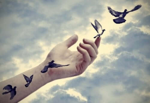 Gökyüzüne uzanmış bir koldaki kuş dövmeleri koldan çıkıp uçmaya başlıyor.