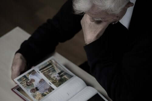Yaşlı bir adam bir fotoğraf albümüne bakıyor.
