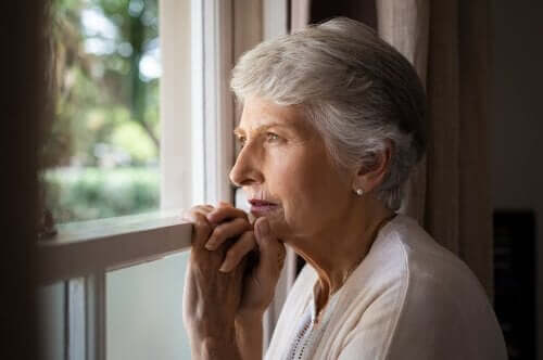 Demansı olan yaşlı bir kadın pencereden bakıyor.