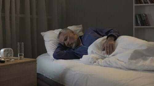 Yatağına yatmış uyuyan yaşlı bir adam.
