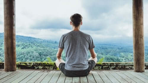 Dağ manzarasına karşı meditasyon yapan bir adam.