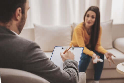 Hastasını dinlerken not alan bir terapist.