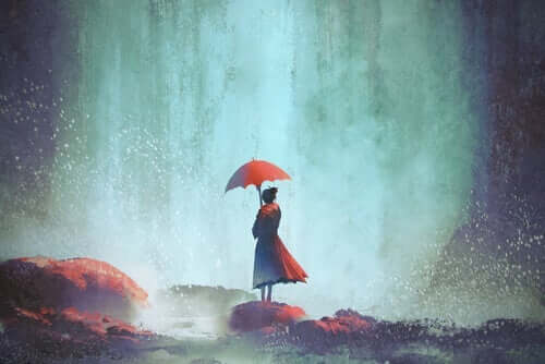 Yağmurda kayaların üstünde şemsiyeyle duran kadın