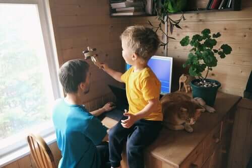 Çocuğu yanındayken evden çalışmak ile uğraşan bir baba.