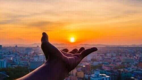 Elini batan güneşe uzatmış bir kişi.