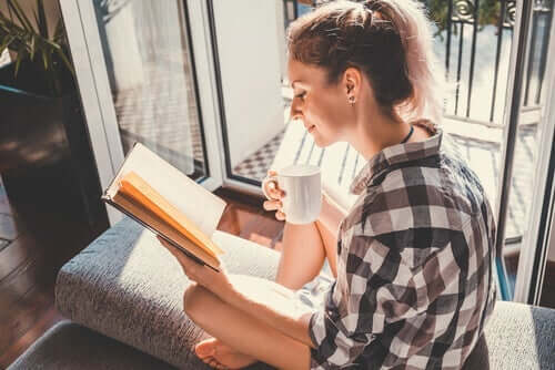 Bir kapının yakınında, güneş altında kitap okuyan bir kadın.