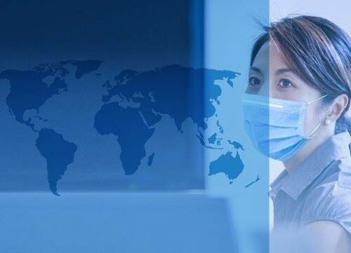 Dünya haritasına doğru bakan maskeli bir kadın.