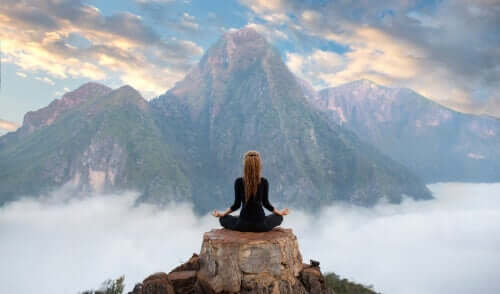 Bir dağın tepesinde meditasyon yapan bir kadın.
