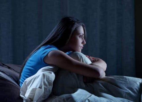 Uykusuzluk hastalığının sonucu gece yatakta oturan kadın