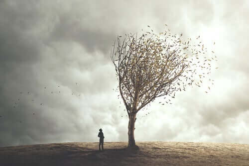 Kuru bir ağacın önünde yalnız duran bir kişi.