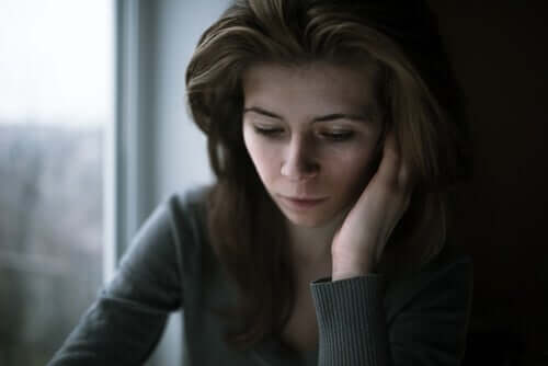 Üzgün görünen, aşağıya bakan bir kadın.