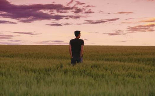 Bir tarlanın ortasında yalnız başına duran bir adam.
