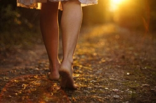 Doğanın içerisinde çıplak ayak yürüyen bir kadın.