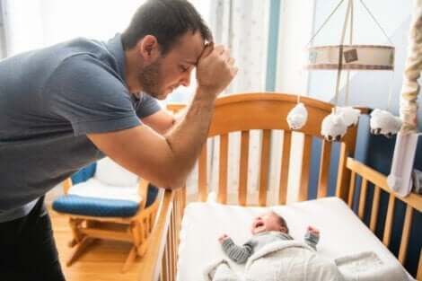 ağlayan bebeğinin başında üzgün duran baba