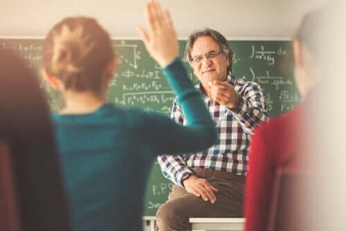 Derste masasına oturmuş el kaldıran öğrencilere söz veren hoca