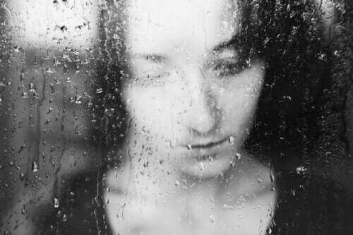 Yağmur yağarken camdan dışarı bakan bir kadın.
