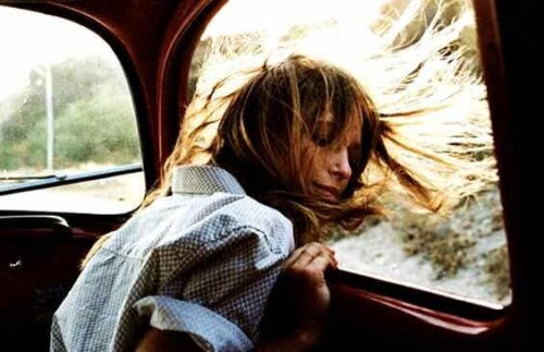 açık araba camından bakarken saçları rüzgarda savrulan kadın