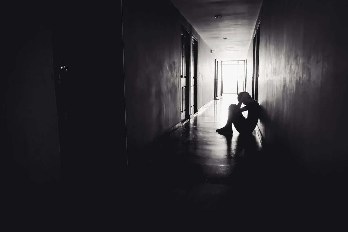 karanlık koridorda oturan üzgün genç