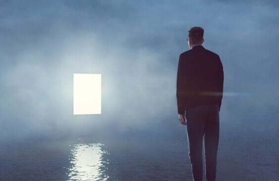 sislerin içindeki ışıklı kapıya bakan adam