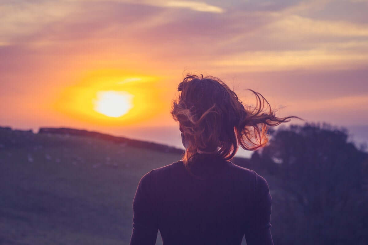 rüzgarda günbatımına bakan kadın
